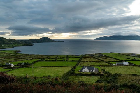 Elevated view over green meadows bordered by natural stone walls and typical cottages to the