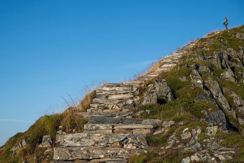 Woman with hiking poles walking up Rørsethornet stone stairs, with 3292 steps one of the longest