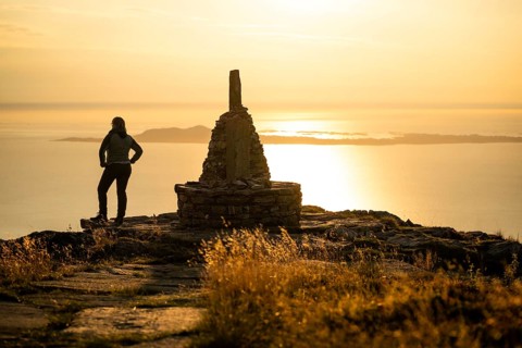 Woman standing next to cairn and looking at the sea, Rørsethornet stone staircase, with 3292 steps