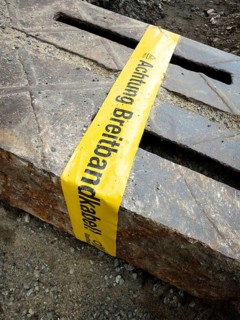 Flapping tape with the indication of an installed fibre optic cable at a construction site in