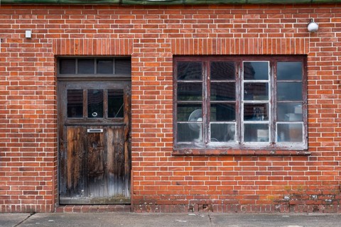 View of the entrance area of an older residential building with a red brick workshop, Uenzen,
