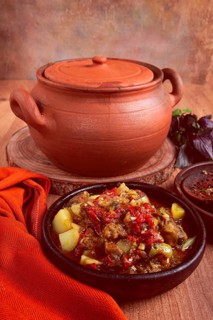 Chanakhi, a Georgian dish. in a clay pot, on a wooden table, stewed meat with vegetables, homemade,