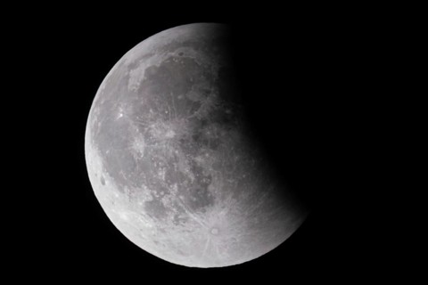 After a total lunar eclipse, the moon appears shortly after its rise in the evening sky as a