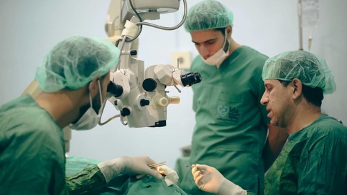 Several doctors performing a complex surgical operation inside an operating room for a displaced