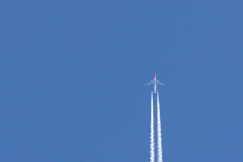 Boeing 737 jet passenger aircraft of Norweign Air with a vapour trial or contrail behind flying in