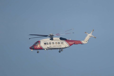 Sikorsky S-92A helicopter of the UK HM Coastguard flying in a blue sky, England, United Kingdom