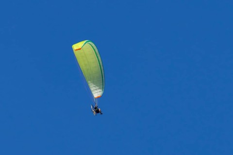 Paraglider flying in a blue sky, England, United Kingdom