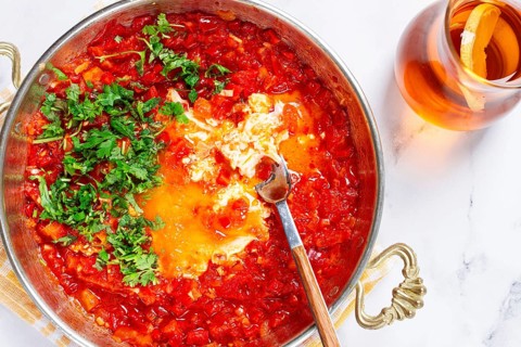 Traditional Turkish dish, scrambled eggs with tomatoes, Menemen, with herbs, in a frying pan,
