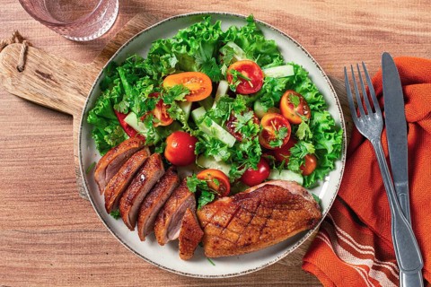 Delicious grilled duck breast served with fresh garden salad and cherry tomatoes at a rustic dining