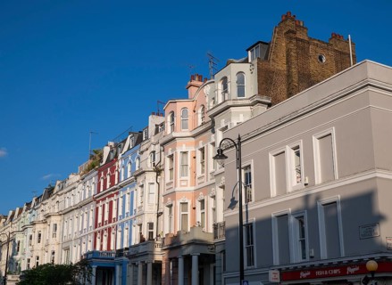 Terraced houses, townhouses with different, colourfully painted facades under a blue sky,