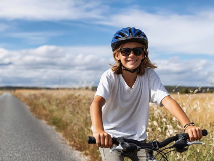 A girl with a bicycle helmet rides a bicycle and smiles friendly into the camera, AI generated, AI