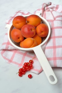 Apricots in a colander and redcurrants