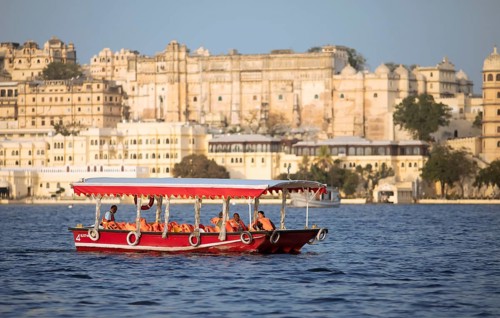 Excursion boat on Lake Pichola, behind the City Palace in the evening light, Udaipur, Rajasthan,