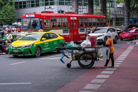 Street crossing woman with cookshop, Bangkok, Thailand
