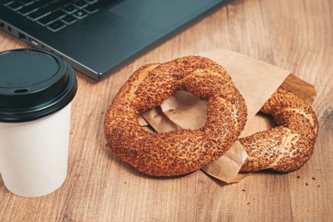 Simits with coffee on a wooden table, with a laptop, in a cozy working environment, snack,