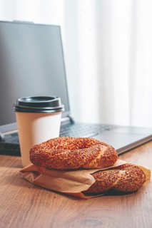 Simits with coffee on a wooden table, with a laptop, in a cozy working environment, snack,