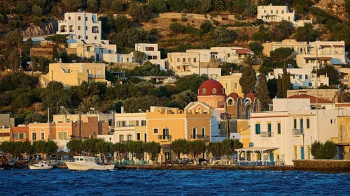 Picturesque waterside village with traditional architecture and a church in hilly terrain, Agia