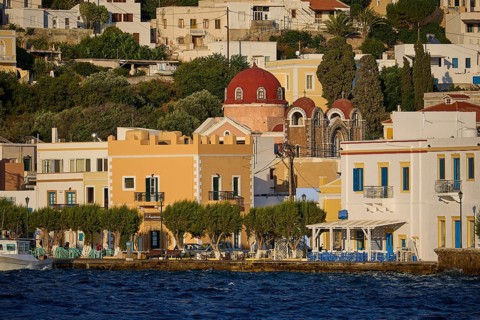 Colourful houses on the waterfront with a church and trees, Greek coastal town ambience, Agia