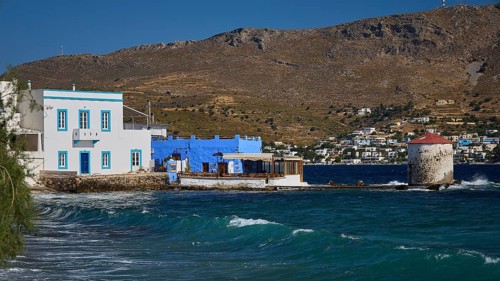 Windmill on the coast with blue and white architecture and undulating sea in the background, Agia