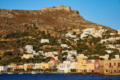 Panteli Fortress, White-blue houses on a hill with an old fortress above, coast in the foreground,