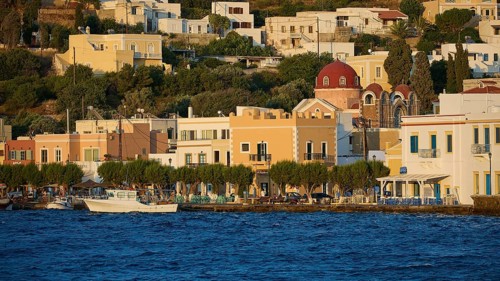 Colourful coastal houses and church by the sea with trees, sunny Greek town view, Agia Marina,