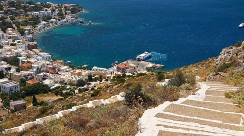 Ormos Alintas, path on a hill overlooking the azure blue sea and a picturesque village on the