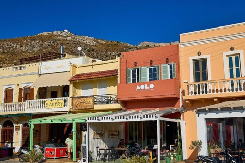 Colourful shops and cafés along a shopping street under a bright blue sky, Agia Marina, Leros,