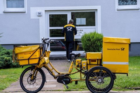 Postman, Deutsche Post, distributes the mail in an apartment building, electric tricycle, North
