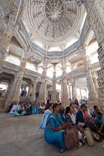 Indian woman praying between the white marble pillars in the Adinath temple in Ranakpur, Jain