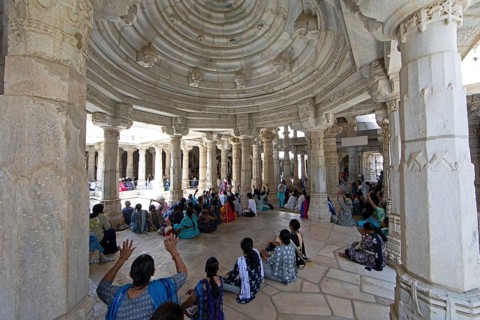 Indian woman praying between the white marble pillars in the Adinath temple in Ranakpur, Jain