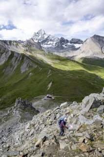 Mountaineer on hiking trail, Glorerhütte mountain hut and mountain peak in the background, Wiener