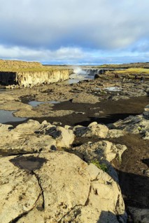 River Jökulsa a Fjöllum flows through canyon, Selfoss waterfall on the horizon, evening sun, North