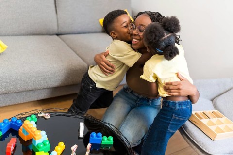 Loving mother enjoying a tender moment with her kids, receiving hugs and kisses in their cozy