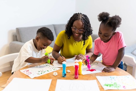 Happy african american family enjoying creative activities at home, painting colorful pictures with