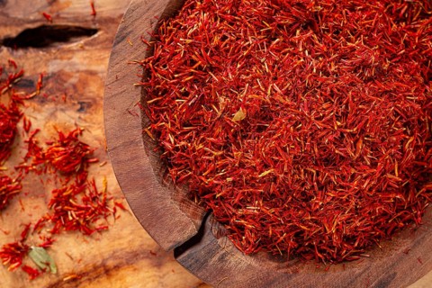Spice saffron threads, in a wooden bowl, on a wooden table, top view, close-up
