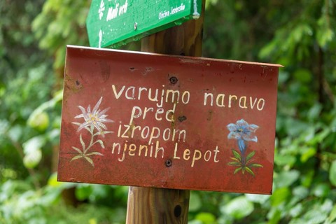 Sign with Slovenian text in front of a green, natural backdrop, Zgornje Jezersko, Gorenjska,