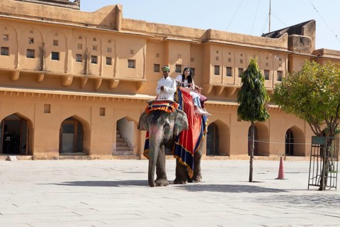 Indian mahout and Indian woman riding a colourfully painted elephant at the Amber Fort or fortress,