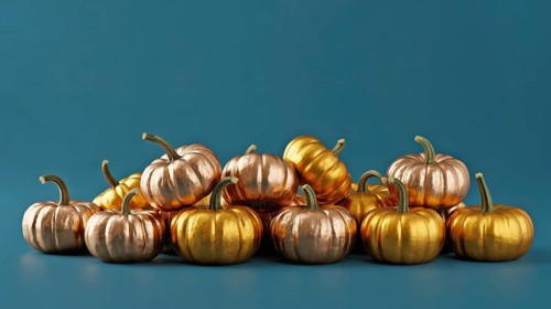 Metallic golden and copper pumpkins piled on blue background. Festive autumn harvest decoration