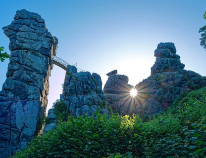 The morning sun shines through an opening in the Externsteine. The Externsteine, a sandstone rock