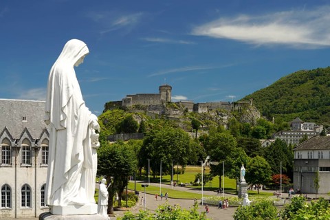 Statue on Rosary Square and the Château fort de Lourdes fortress in the Marian pilgrimage town of