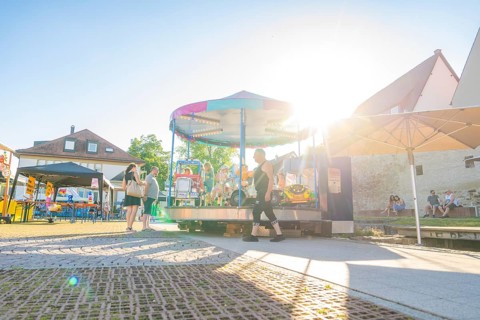 A carousel in the sunlight attracts cheerful people on a summer's day, 950 years of Weil der Stadt