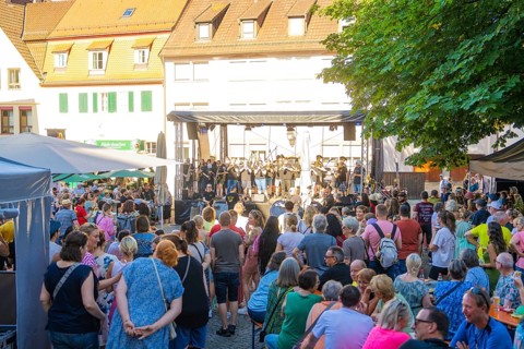 A large crowd gathers around a stage during a concert at a town festival, 950 years Weil der Stadt