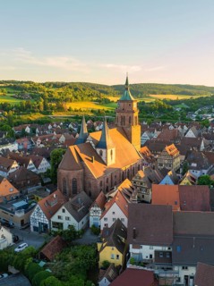 Historic church in the middle of a town with hills in the background in warm evening light, 950