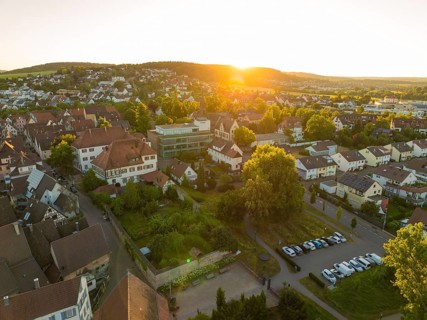 Sunset over a village with car parks, surrounded by lush nature and peaceful countryside, 950 years