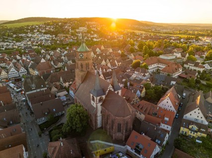 Aerial view of a church surrounded by an idyllic cityscape at sunset, 950 years Weil der Stadt