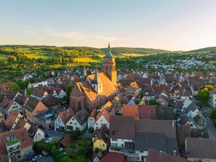 A picturesque village with a church under warm evening light in a hilly landscape, 950 years Weil