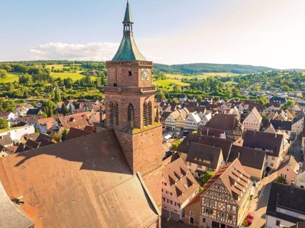 Church tower overlooks a hilly, rural landscape and a village with half-timbered houses, 950 years
