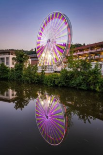 Ferris wheel at night with colourful lights reflected in the water, Calw, Germany