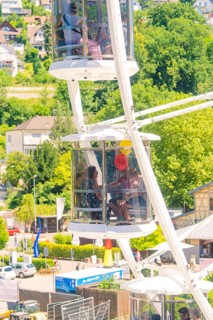 People in a Ferris wheel gondola with a view of green landscape and sunny weather, Calw, Germany