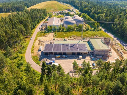 Construction work in a rural setting with solar energy on the roofs and surrounded by forest, new